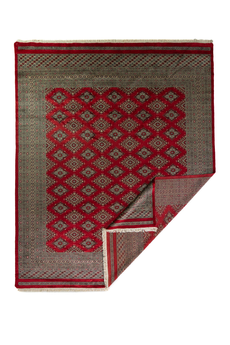 Alfombra Persa Bukara Yamouth rojo de 2.49 x 3.07 mts, vista completa con una esquina doblada; se observan retícula de rombos y motivos geométricos repetidos