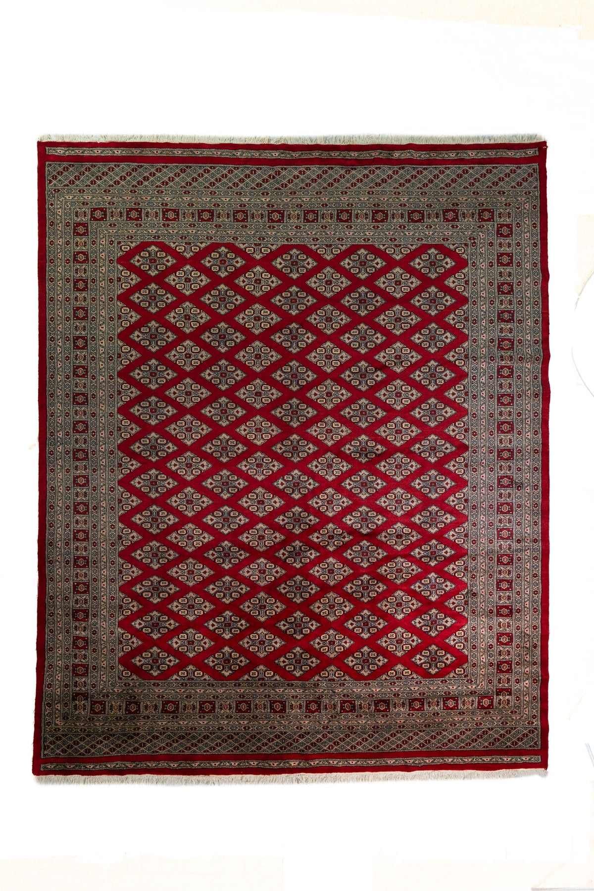 Alfombra Persa Bukara Yamouth rojo de 2.49 x 3.07 mts, vista completa vertical con retícula de rombos; se observan entramado de rombos y guardas geométricas de alto contraste