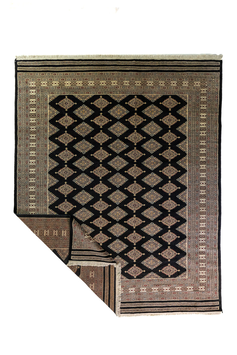 Alfombra Persa Bukara Yamouth negro de 2.03 x 3.10 mts, vista completa con una esquina doblada; se observan rombos claros repetidos sobre campo oscuro y guarda ornamental