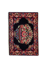Alfombra Persa Horazan azul y rojo de 0.72 x 1.02 mts, vista completa de la pieza con un gran medallón floral sobre un campo azul oscuro, acompañado por una guarda roja y motivos vegetales