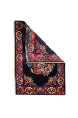 Alfombra Persa Horazan azul y rojo de 0.72 x 1.02 mts, vista con una esquina doblada para mostrar guarda, reverso y estructura visual
