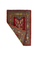Alfombra Caucasica Kazak ladrillo y Multicolor de 0.70 x 1.00 mts, vista con una esquina doblada para mostrar guarda, reverso y estructura visual