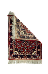 Alfombra Persa Karadja rojo y azul de 0.70 x 0.95 mts, vista con una esquina doblada para mostrar guarda, reverso y estructura visual