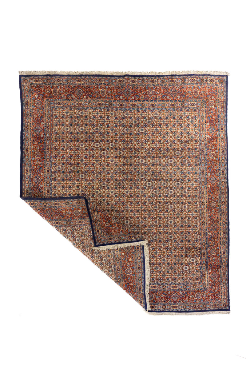 Alfombra clásica con una esquina levantada, mostrando el reverso, los flecos y la flexibilidad del tejido artesanal.