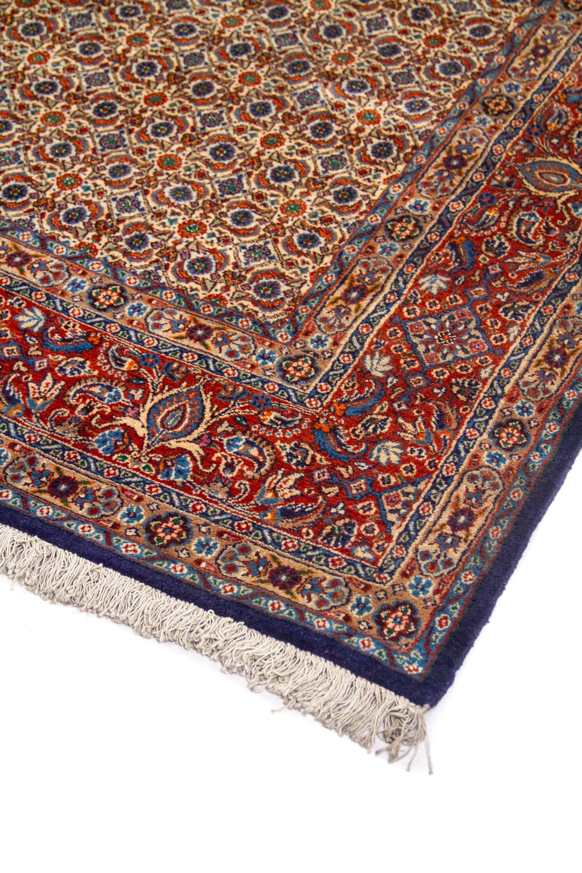 Detalle en perspectiva de alfombra con pequeño patrón geométrico repetido, borde rojo ornamental y terminación azul oscuro.