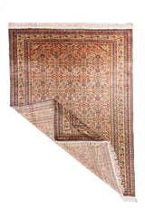 Alfombra oriental tradicional con una esquina doblada que permite ver el reverso, la estructura del tejido y los flecos en tono blanco suave.
