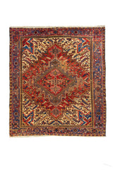 Alfombra estilo tribal con gran medallón geométrico rojo, fondo beige y guarda azul con motivos en rojo y dorado.