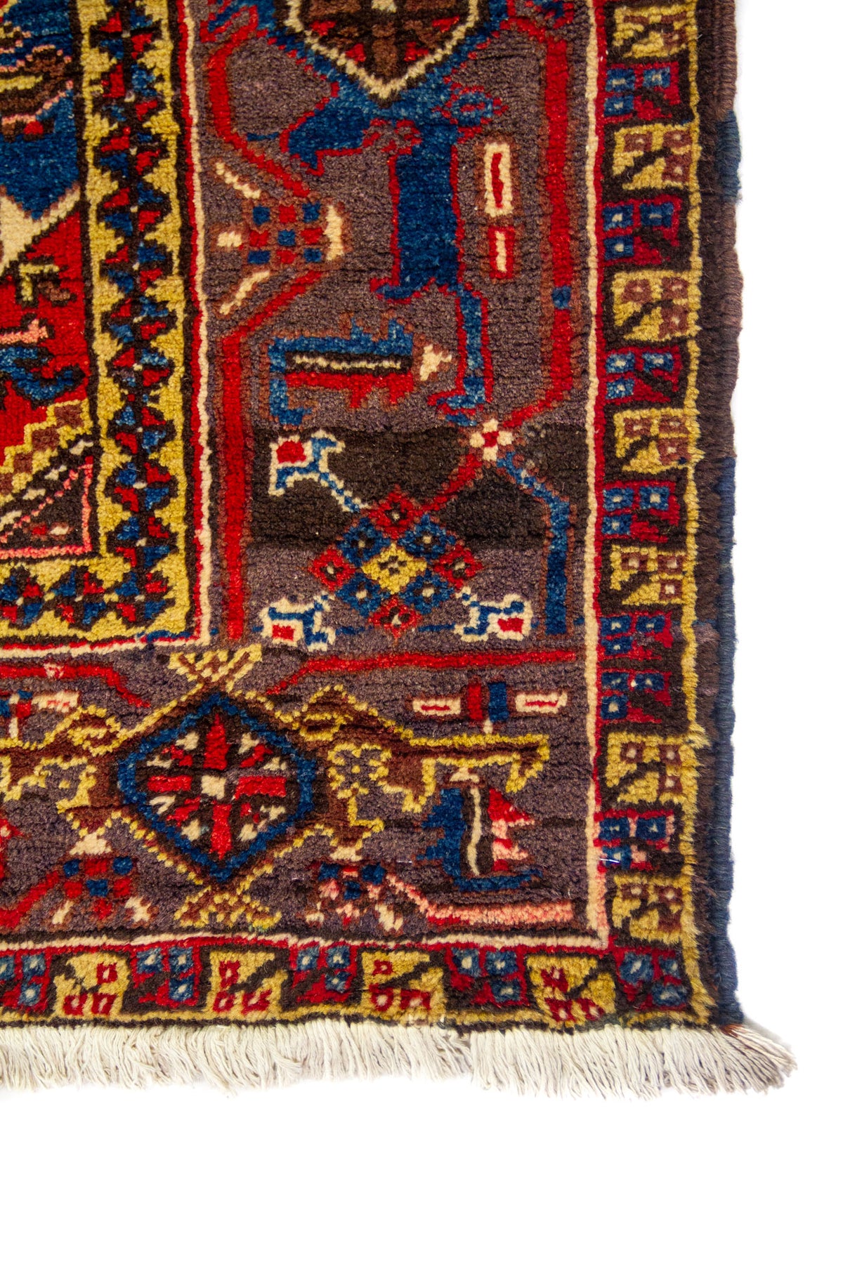 Primer plano de la esquina con guarda azul y detalles geométricos; flecos claros visibles en el borde inferior.