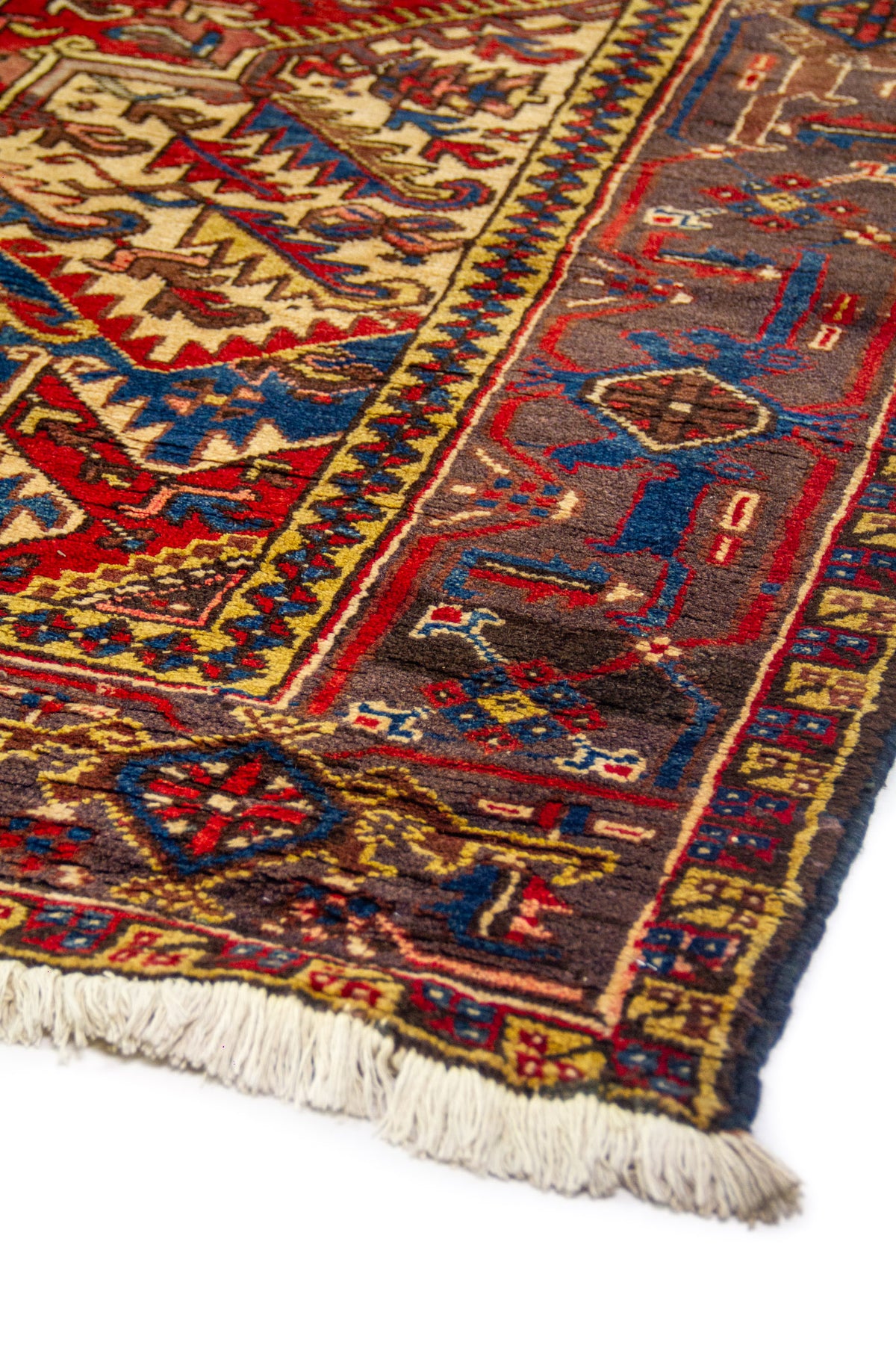 Detalle de la orilla con motivos tribales en azul, rojo y amarillo; textura del pelo y remate del borde.