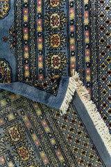 Alfombra Persa Bukara celeste de 2.77 x 3.75 mts doblada, con detalle de guarda, reverso y flecos