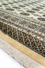 Alfombra Persa Bukara beige de 2.88 x 3.68 mts, detalle del campo beige y la guarda; se observan medallones ovalados repetidos y guardas geométricas