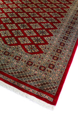 Alfombra Persa Bukara Yamouth rojo de 2.49 x 3.07 mts, vista en perspectiva del campo y la guarda; se observan entramado de rombos y guardas geométricas de alto contraste