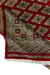 Alfombra Persa Bukara Yamouth rojo de 2.49 x 3.07 mts, detalle de pliegue y guarda; se observan entramado de rombos y guardas geométricas de alto contraste