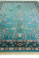 Alfombra Persa Nain verde y celeste de 2.35 x 3.00 mts, vista en perspectiva del campo floral y la guarda; se observan motivos florales y vegetales continuos con guarda ornamental