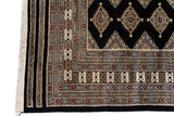 Alfombra Persa Bukara Yamouth negro de 2.03 x 3.10 mts, detalle de esquina y guarda; se observan rombos claros repetidos sobre campo oscuro y guarda ornamental