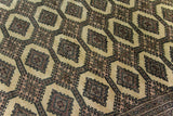 Alfombra Persa Bukara Yamouth marrón y beige de 2.20 x 3.05 mts, detalle cercano del campo y los motivos; se observan motivos alargados y rombos repetidos sobre campo oscuro