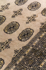 Alfombra Persa Bukara Yamouth beige de 2.19 x 3.00 mts, detalle de medallón y patrón repetido; se observan medallones ovalados repetidos dentro de una composición ordenada