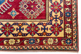 Alfombra Caucasica Kazak rojo y beige de 2.77 x 2.08 mts, detalle de guarda geométrica y flecos; se observan medallones y motivos geométricos caucásicos de fuerte contraste