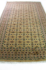 Alfombra Persa Bukara Yamouth beige de 1.83 x 2.90 mts, vista en perspectiva del campo beige; se observan pequeños motivos geométricos repetidos y guardas de tono suave