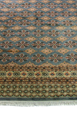 Alfombra Persa Bukara Yamouth celeste de 1.88 x 2.85 mts, vista en perspectiva del campo y las guardas; se observan motivos pequeños repetidos y guardas geométricas contrastantes