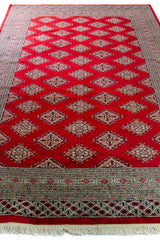 Alfombra Persa Bukara Yamouth rojo de 1.88 x 2.85 mts, vista en perspectiva del campo rojo; se observan retícula geométrica y guardas claras de contraste