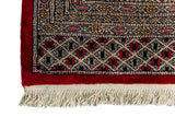 Alfombra Persa Bukara Yamouth rojo de 1.88 x 2.85 mts, detalle de guarda y flecos; se observan retícula geométrica y guardas claras de contraste