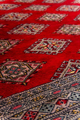 Alfombra Persa Bukara Yamouth rojo de 1.88 x 2.85 mts, detalle del patrón geométrico; se observan retícula geométrica y guardas claras de contraste