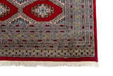 Alfombra Persa Bukara Yamouth rojo de 1.90 x 2.90 mts, detalle de guarda y flecos; se observan medallones ovalados repetidos y guardas de varios niveles