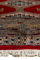 Alfombra Persa Bukara Yamouth rojo de 1.90 x 2.90 mts, detalle cercano de textura visual y borde; se observan medallones ovalados repetidos y guardas de varios niveles