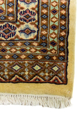 Alfombra Persa Bukara Yamouth beige de 1.88 x 2.90 mts, detalle de esquina, guarda y flecos; se observan retícula geométrica con detalles de color en las guardas