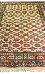 Alfombra Persa Bukara Yamouth beige de 1.88 x 2.90 mts, vista en perspectiva del campo y las guardas; se observan retícula geométrica con detalles de color en las guardas