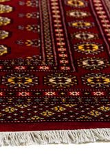 Alfombra Persa Bukara rojo de 1.85 x 2.75 mts, detalle cercano de guarda y flecos; se observan columnas de medallones ovalados y guardas geométricas