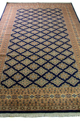 Alfombra Persa Yamouth azul de 1.85 x 2.85 mts, vista en perspectiva del campo y la guarda; se observan retícula de rombos azules sobre campo claro