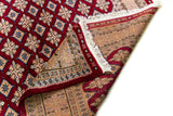 Alfombra Persa Yamouth rojo de 1.83 x 2.87 mts, detalle de pliegue, reverso y terminación; se observan retícula geométrica sobre campo intenso y guarda clara