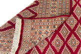 Alfombra Persa Yamouth rojo de 1.83 x 2.87 mts, detalle de pliegue, reverso y terminación; se observan patrón geométrico repetitivo con guardas ornamentales