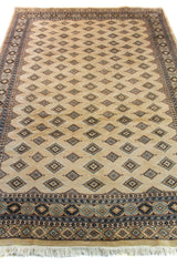 Alfombra Persa Yamouth beige de 1.55 x 2.44 mts, vista en perspectiva del campo claro; se observan pequeños motivos geométricos repetidos y guardas sobrias