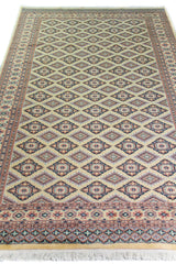 Alfombra Persa Yamouth beige de 1.55 x 2.54 mts, vista en perspectiva del campo beige; se observan rombos repetidos y guardas geométricas de contraste