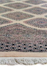 Alfombra Persa Yamouth marrón y beige de 1.60 x 2.54 mts, detalle de guarda y flecos; se observan retícula geométrica clara sobre campo oscuro