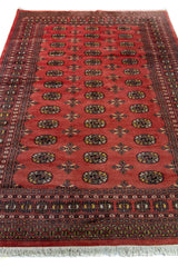 Alfombra Persa Yamouth rosa de 1.56 x 2.40 mts, vista en perspectiva del campo rosa terracota; se observan medallones ovalados repetidos y guardas oscuras