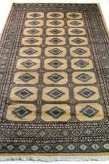 Alfombra Persa Yamouth beige de 1.55 x 2.44 mts, vista en perspectiva del campo y la guarda oscura; se observan medallones rectangulares repetidos y guardas oscuras
