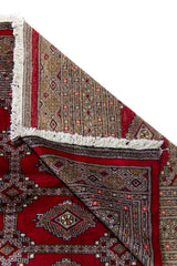 Alfombra Persa Yamouth rojo de 1.58 x 2.36 mts, detalle de pliegue, reverso y borde; se observan medallones ovalados destacados y guardas rojizas