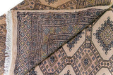 Alfombra Persa Yamouth marrón y beige de 1.52 x 2.44 mts, detalle de pliegue, reverso y patrón; se observan grandes rombos claros y guardas oscuras