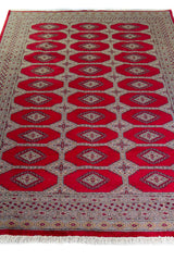 Alfombra Persa Yamouth rojo de 1.70 x 2.37 mts, vista en perspectiva del campo y las guardas; se observan medallones ovalados repetidos y guardas contrastantes