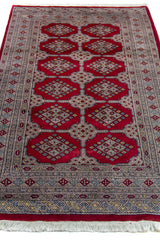 Alfombra Persa Bukara Yamouth rojo de 1.22 x 1.93 mts, detalle cercano de motivos y terminación; el diseño muestra una retícula vertical de medallones enlazados y guardas geométricas finas