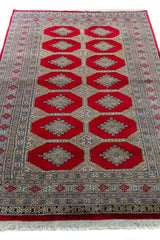 Alfombra Persa Bukara Yamouth rojo de 1.27 x 2.00 mts, vista en perspectiva del campo y las guardas; el diseño muestra medallones geométricos repetidos en dos columnas y un marco ornamental de alto contraste