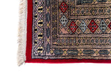 Alfombra Persa Bukara Yamouth rojo de 1.27 x 2.00 mts, detalle cercano de motivos y terminación; el diseño muestra medallones geométricos repetidos en dos columnas y un marco ornamental de alto contraste