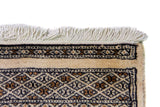 Alfombra Persa Bukara Yamouth beige de 1.24 x 1.73 mts, detalle de guarda, borde y textura; el diseño muestra medallones ovalados oscuros alineados sobre un campo claro y guardas geométricas profundas