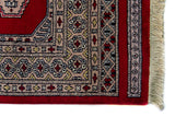 Alfombra Persa Yamouth rojo de 1.25 x 1.90 mts, detalle de guarda, borde y textura; el diseño muestra dos columnas de medallones claros sobre un campo rojo y un borde geométrico oscuro