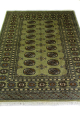 Alfombra Persa Bukara Yamouth verde de 1.24 x 1.78 mts, vista en perspectiva del campo y las guardas; el diseño muestra medallones ovalados repetidos sobre un campo verdoso y guardas geométricas oscuras