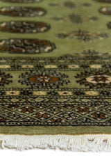 Alfombra Persa Bukara Yamouth verde de 1.24 x 1.78 mts, detalle de guarda, borde y textura; el diseño muestra medallones ovalados repetidos sobre un campo verdoso y guardas geométricas oscuras